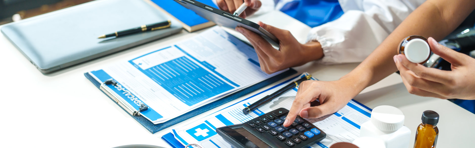 A close-up of two doctors discussing a bottle of medicine at a table in hospital.They collaborate